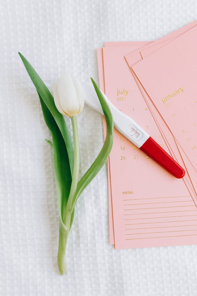 Close-up of a pregnancy test and tulip on a calendar, symbolizing new beginnings.