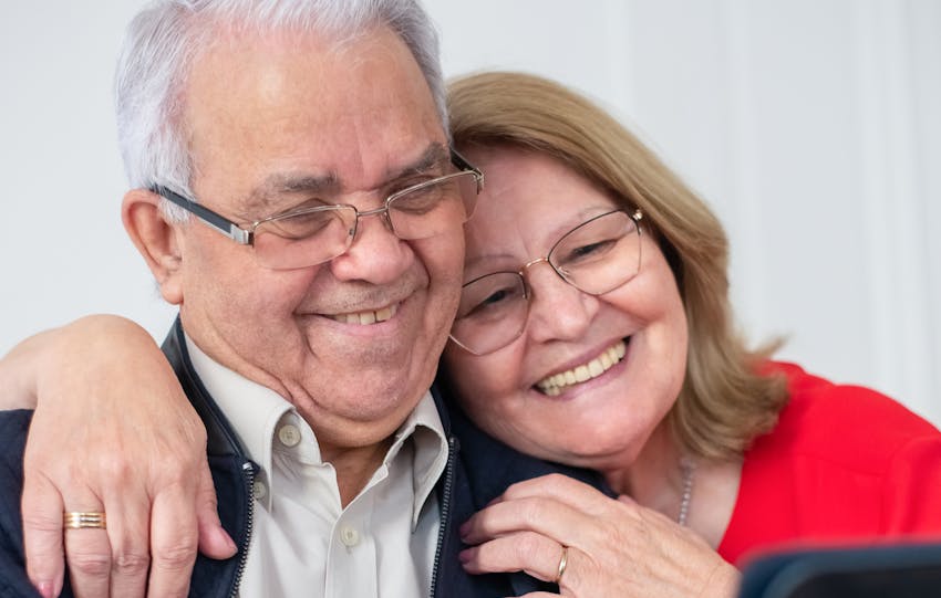 Happy senior couple smiling while making a video call at home, connected and joyful.