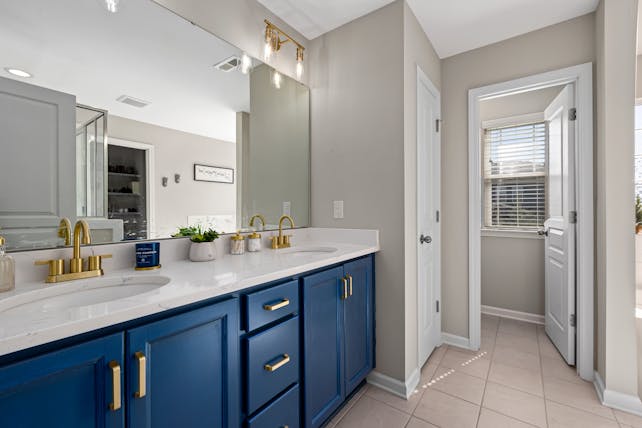 Stylish bathroom featuring a blue vanity, gold fixtures, and decorative accents for a modern home interior.