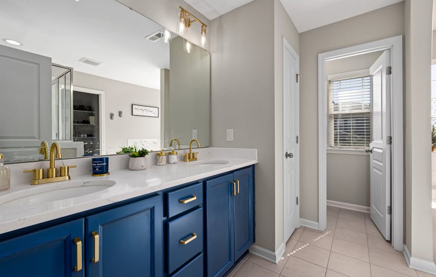 Stylish bathroom featuring a blue vanity, gold fixtures, and decorative accents for a modern home interior.